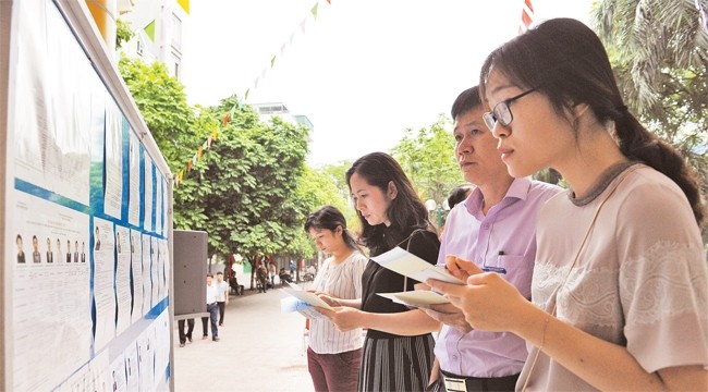 Cử tri khu bỏ phiếu số 8 phường Nhân Chính, quận Thanh Xuân xem danh sách niêm yết người ứng cử đại biểu Quốc hội và đại biểu HĐND các cấp. Ảnh: DUY LINH