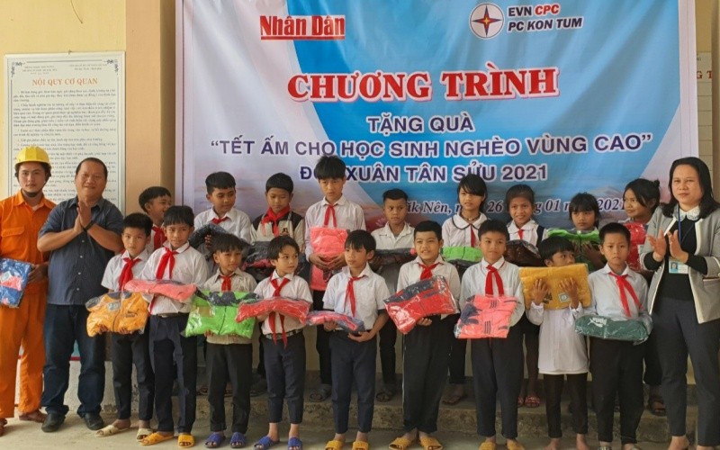 Phóng viên Báo Nhân Dân cùng đại diện Công ty Điện lực Kon Tum trao áo ấm cho các em học sinh Trường PTDT bán trú tiểu học Đắk Nên.
