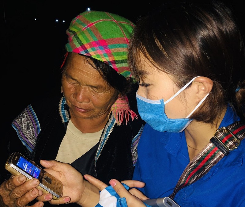 Thanh niên tình nguyện hướng dẫn một người dân tộc thiểu số ở Lai Châu cài đặt Bluezone.