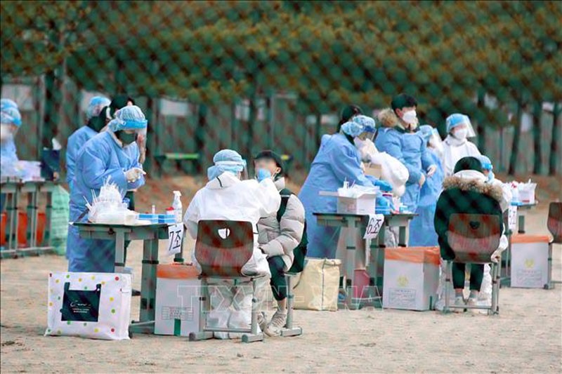 Nhân viên y tế lấy mẫu xét nghiệm Covid-19 cho học sinh tại Gwangju, Hàn Quốc, ngày 28/12/2021. (Ảnh: Yonhap/TTXVN)