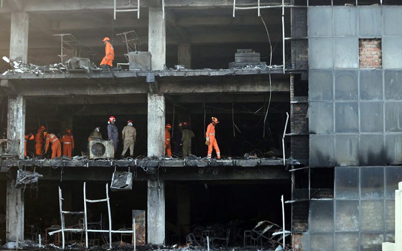 Lực lượng cứu hộ triển khai tại hiện trường vụ cháy ở New Delhi. (Ảnh REUTERS)