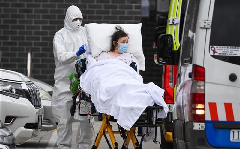 Nhân viên y tế chuyển bệnh nhân Covid-19 lên xe cứu thương tại thành phố Melbourne, Australia. (Ảnh: AFP/TTXVN)