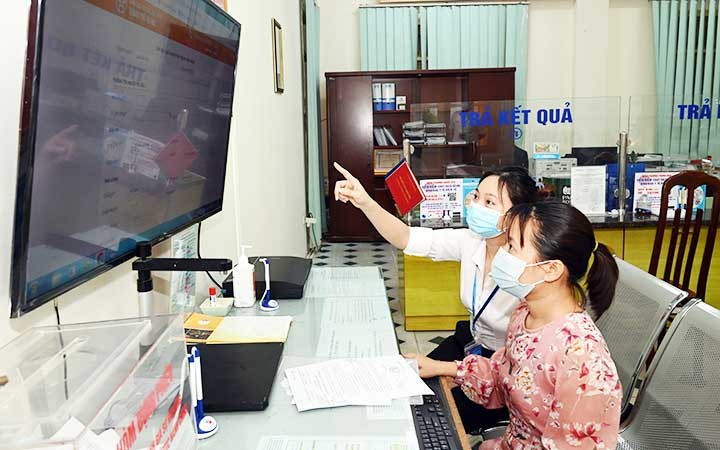Cán bộ UBND phường Trung Hòa, quận Cầu Giấy (Hà Nội) hướng dẫn người dân thực hiện thủ tục hành chính trực tuyến. (Ảnh: MINH HÀ)