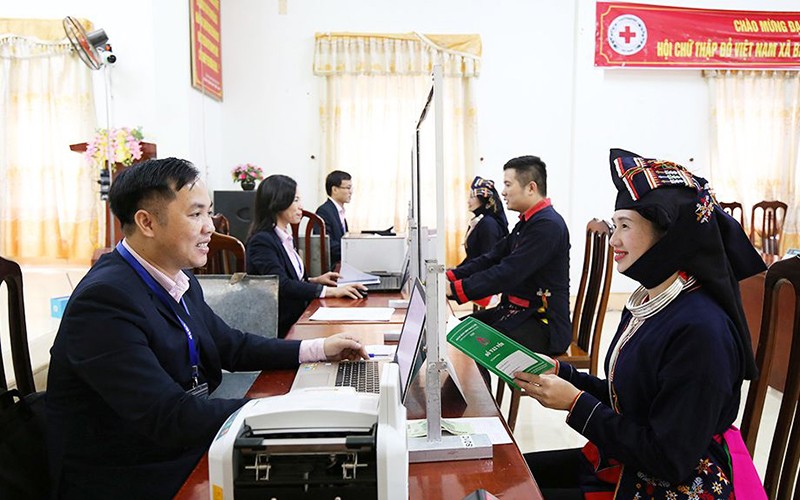 Cán bộ Ngân hàng Chính sách xã hội Hà Nội làm thủ tục cho đồng bào Dao ở xã Ba Vì, huyện Ba Vì nhận vốn vay. (Ảnh VIỆT HẢI) 