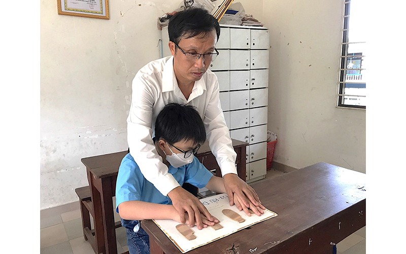 Thầy Hoàng Văn Khương hướng dẫn học môn Lịch sử cho một học sinh khiếm thị.