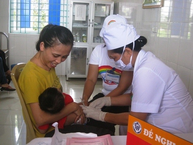 Các y, bác sĩ trạm y tế xã Quảng Bình tiêm vắc xin phòng bệnh cho trẻ em.